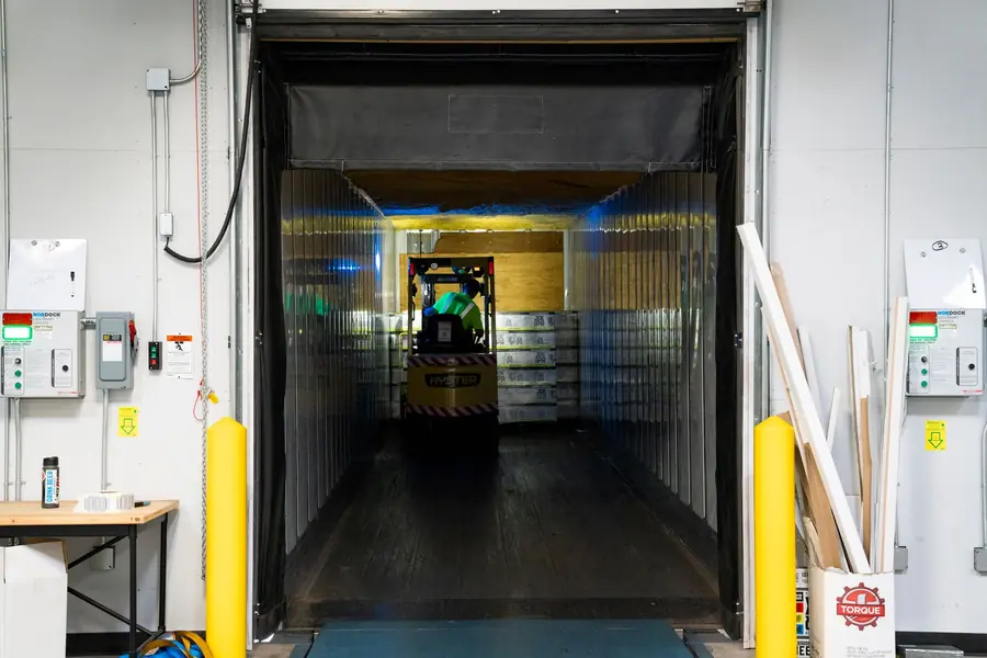 Open loading door of a refrigerated cold store with a forklift inside, the kind of load a business battery may need to support