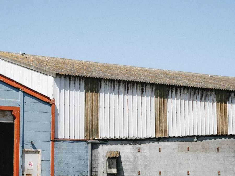 Older industrial shed with corrugated cement sheet roof and painted cladding, the kind of roof that needs checking before solar