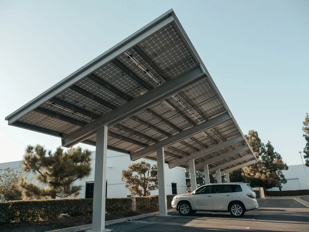 Solar carport canopy on a steel frame shading a parked car beside an office building