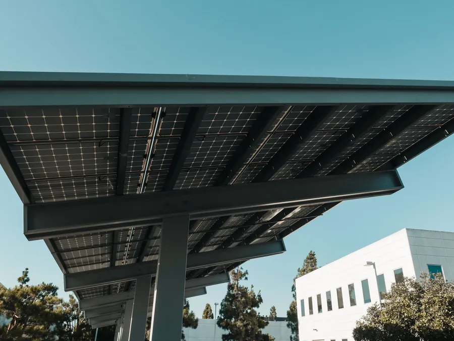 Looking up at the steel frame and underside of a solar carport canopy next to an office block