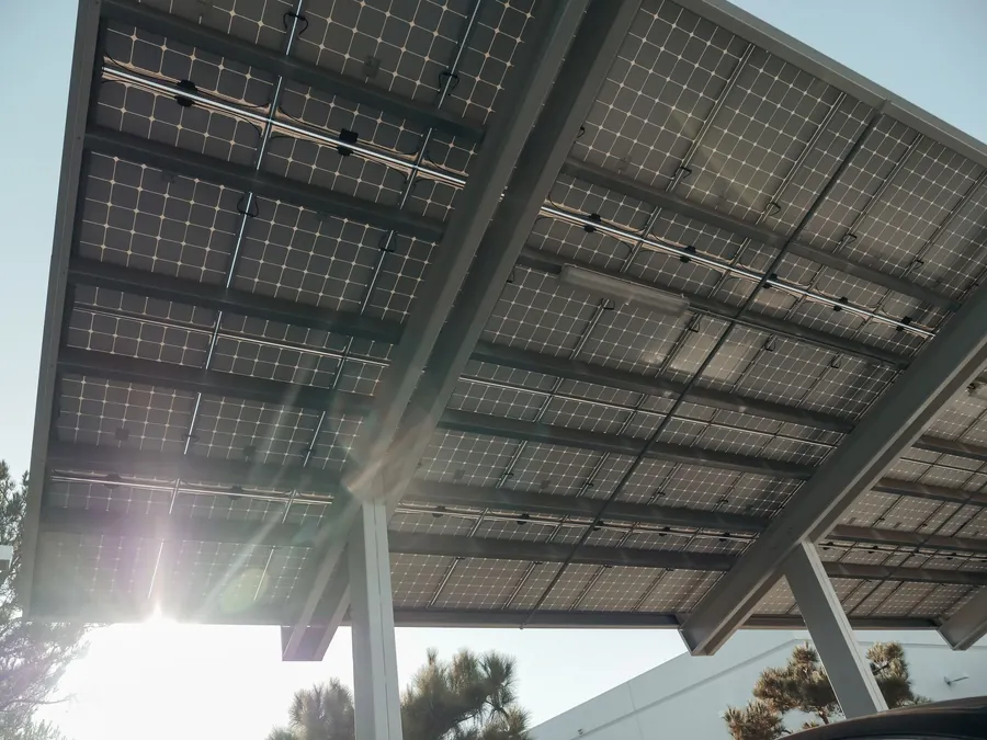 Underside of a solar carport canopy with sunlight showing between the panels